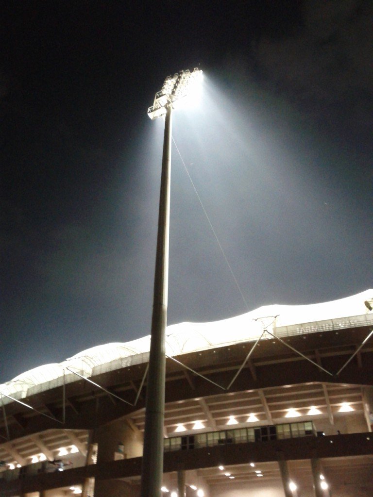 A cricket stadium scoreboard during a night match