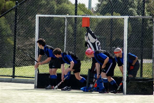 Field hockey penalty corner action with attackers and defenders around the circle