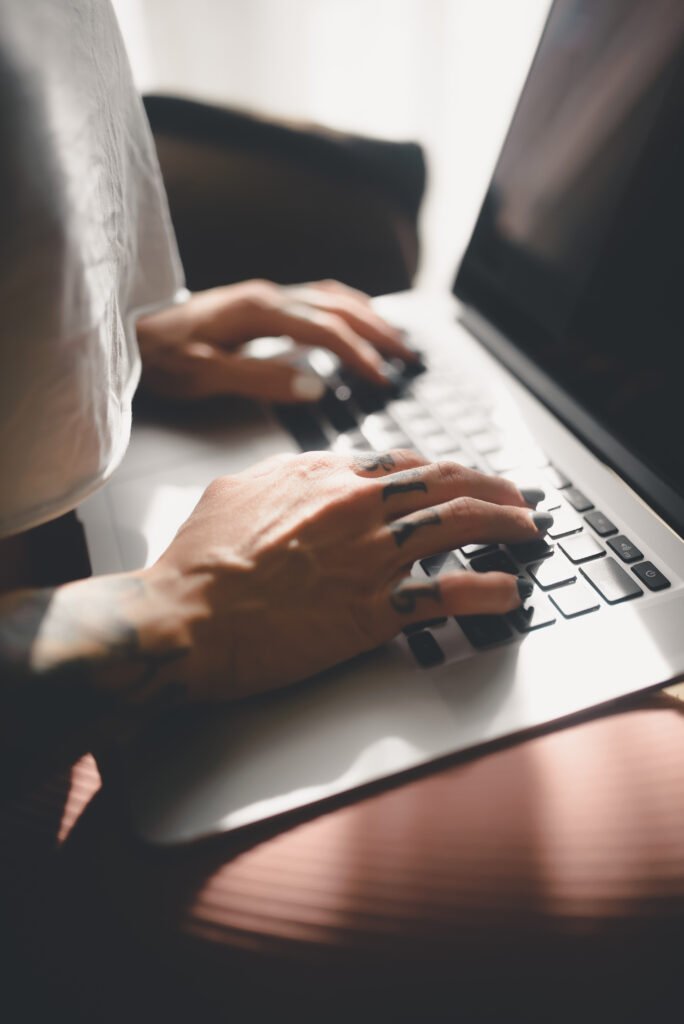Hands typing on a laptop keyboard at a desk