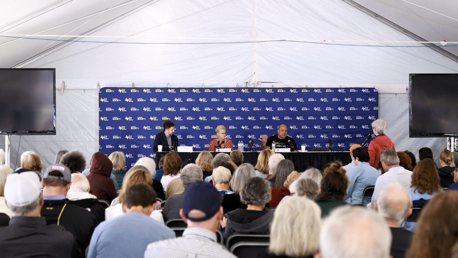 Panel discussion on a conference stage with speakers at a table