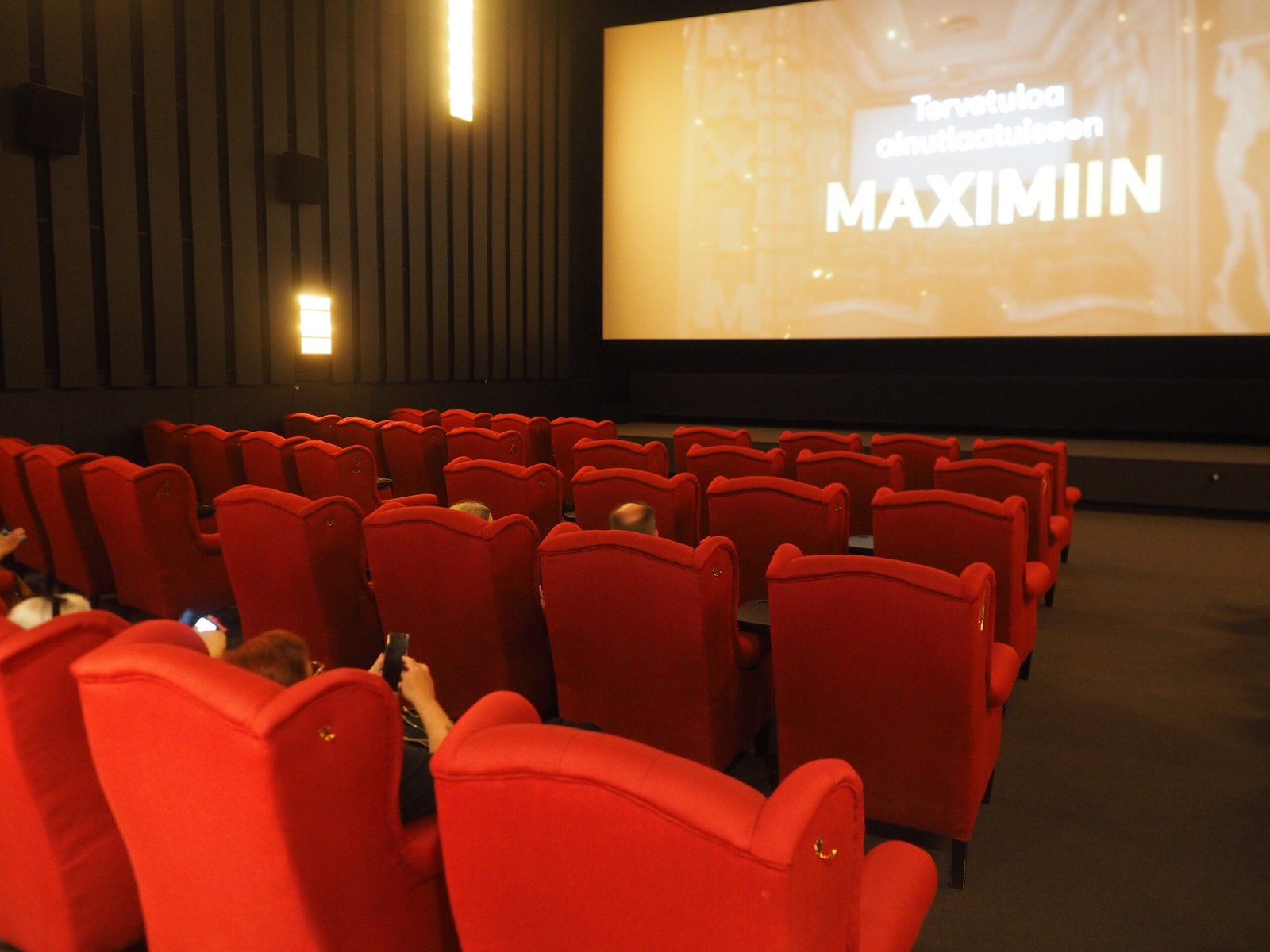 A cinema auditorium with rows of seats facing a large screen