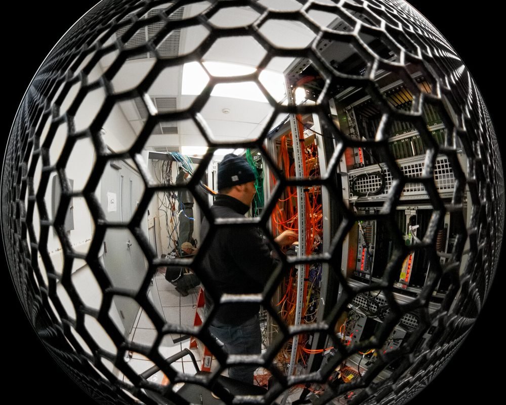 Technician working on server racks in a data centre, fisheye view