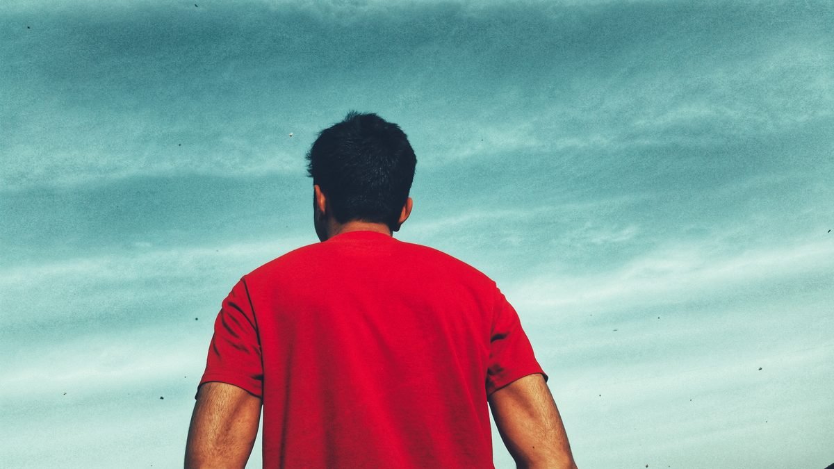 Man in a red shirt watching kites in the sky during the Basant festival