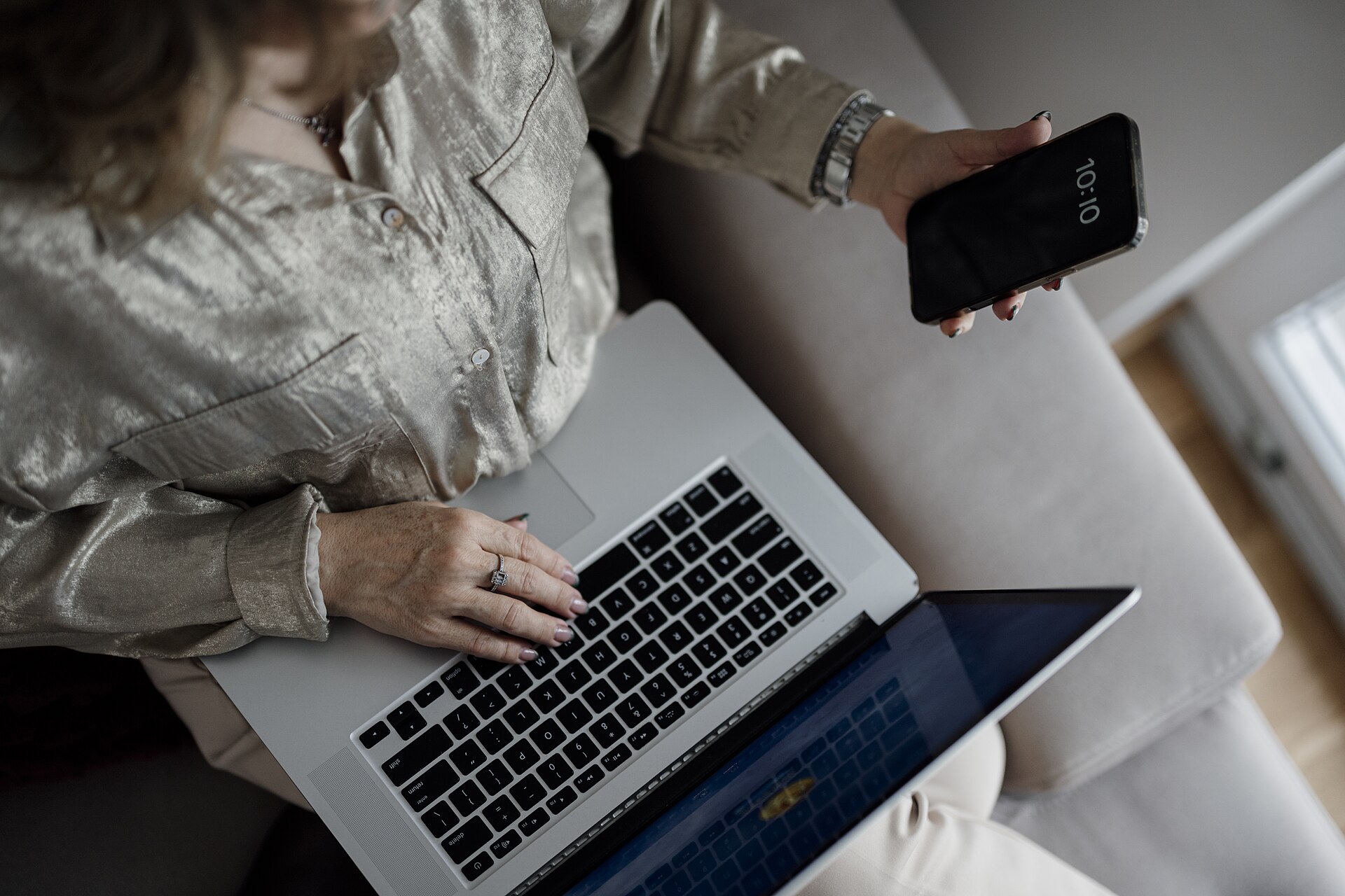 Person using a laptop and smartphone — the PTA warns attackers now use AI-written phishing, voice cloning and deepfakes to steal credentials