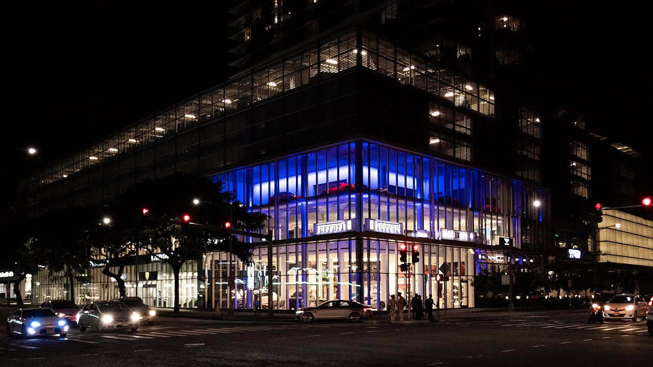 Car showroom exterior at night with new vehicles on display