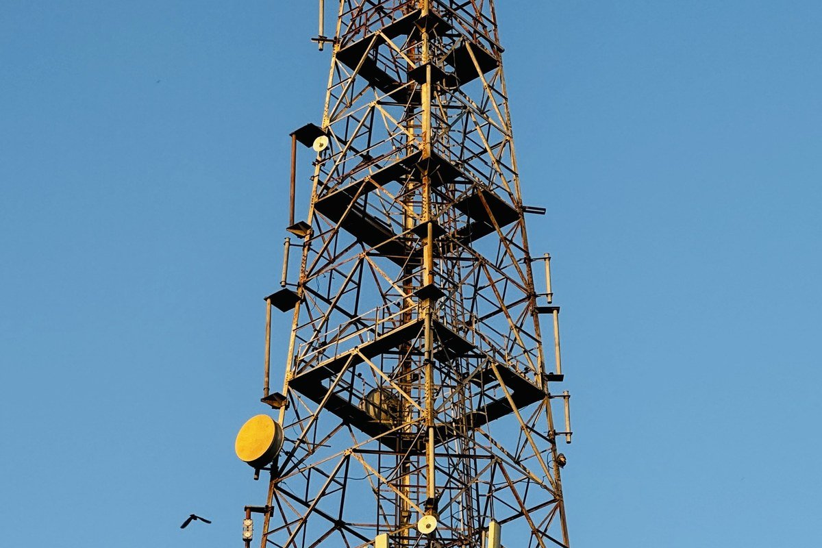 A mobile communications tower with antennas against a clear blue sky